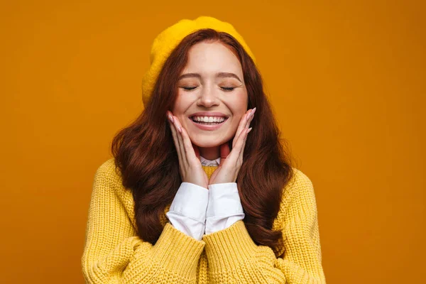 幸せな若いです女性とともに長い赤い髪でセーターとベレー帽立って上黄色の壁の背景 目を閉じて — ストック写真