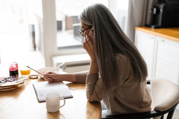 Gammal Grå Kvinna Pratar Mobiltelefon När Hon Arbetar Köket Hemma — Stockfoto