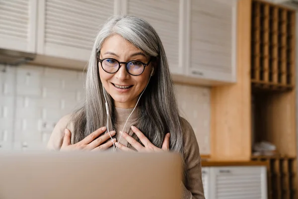 Leende Kvinna Gestikulerar När Använder Hörlurar Och Laptop Köket Hemma — Stockfoto