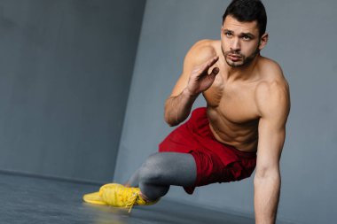 Genç üstsüz sporcu içeride çalışırken egzersiz yapıyor.