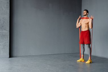 Genişletici bantla egzersiz yapan genç üstsüz sporcu.