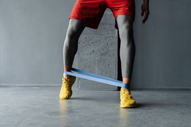 Beyaz sporcu içeride genişletici bantla egzersiz yapıyor.