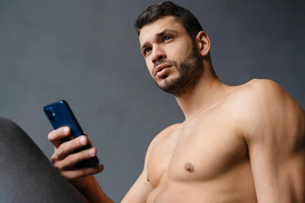 Joven Deportista Sin Camisa Usando Teléfono Móvil Mientras Hace Ejercicio — Foto de Stock