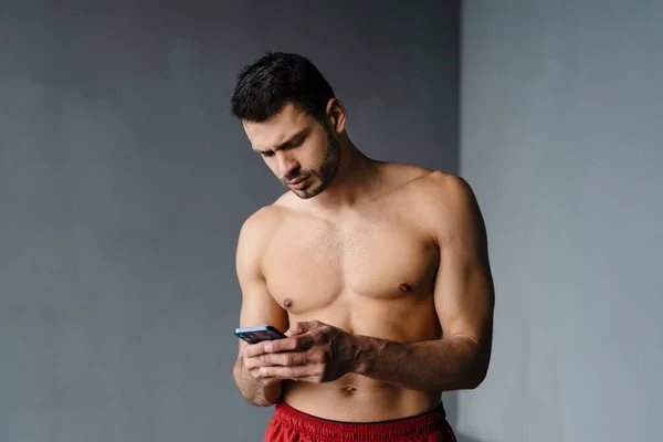 Joven Deportista Sin Camisa Usando Teléfono Móvil Mientras Hace Ejercicio — Foto de Stock