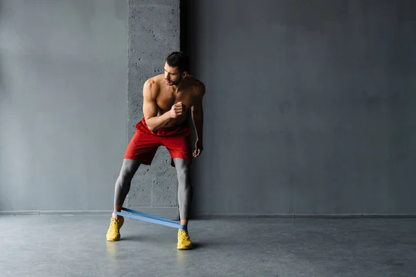 年轻的赤身裸体运动员在室内用膨胀带做运动 — 图库照片