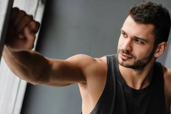 Young White Puzzled Sportsman Looking Out Window Indoors — Stock Photo, Image