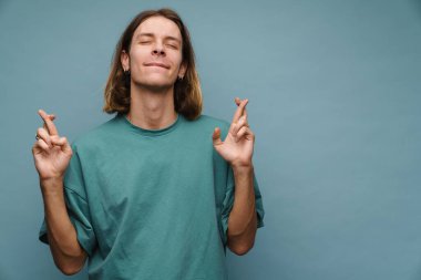 Tişörtlü gülümseyen sarışın bir adamın portresi mavi arka planda durup şans dilemek için şans diliyor.