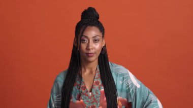 Kameraya poz veren muhteşem Afrikalı Amerikalı kadının yakın plan görüntüsü. Stüdyonun kırmızı arka planında izole edilmiş kimono elbiseler giyiyor.