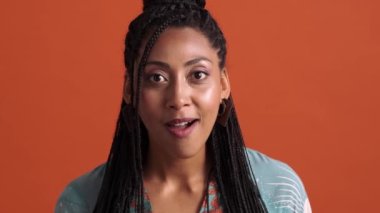 Stüdyodaki kırmızı arka planda mahsur kalmış afro-amerikan bir kadının sevinç dolu görüntüsü.