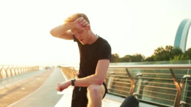 Bir sporcu, köprüdeki eğitimden sonra alnından ter siler.