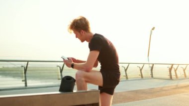 Köprüdeki eğitimden sonra cep telefonunu kontrol eden bir sporcunun yan görüntüsü.