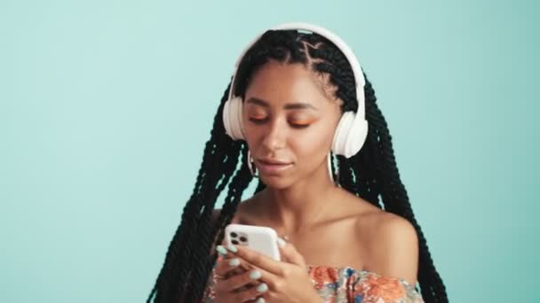 Una Mujer Africana Guapa Escuchando Música Usando Auriculares Mientras Sostiene — Vídeo de stock