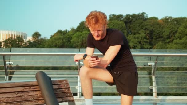 Een Sporter Controleert Zijn Mobiel Een Training Buiten Brug — Stockvideo