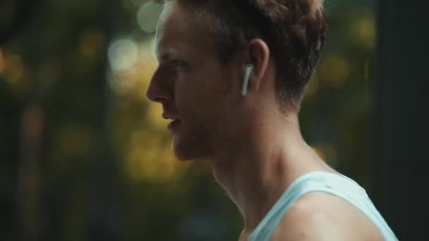 Widok Bliska Sportowca Noszącego Słuchawki Bezprzewodowe Korzystającego Nadajnika Fitness Podczas — Wideo stockowe
