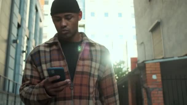 Привлекательный Африканский Американец Клетчатой Рубашке Гуляющий Улице Используя Свой Телефон — стоковое видео