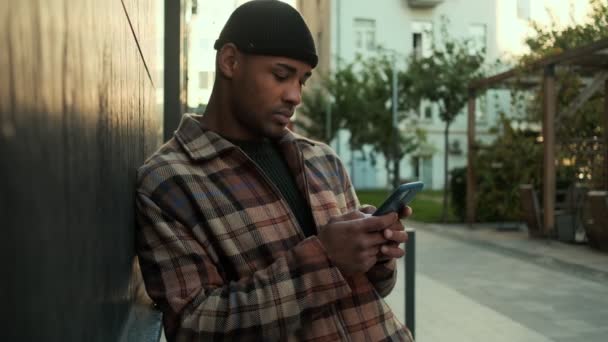 Позитивный Африканский Американец Одетый Клетчатую Рубашку Используя Свой Телефон Печатающий — стоковое видео