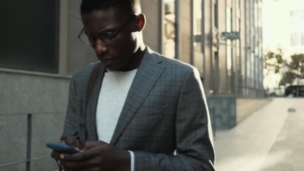 Serio Hombre Negocios Afroamericano Caminando Por Calle Mientras Mira Móvil — Vídeo de stock