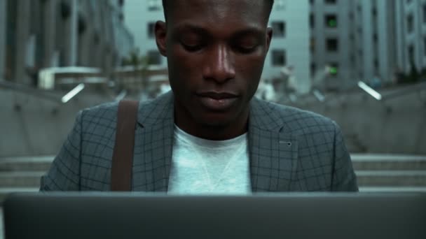 在市中心的大街上 一位专注的非洲商人一边拿着笔记本电脑一边对着摄像机 一边拍着近照 — 图库视频影像