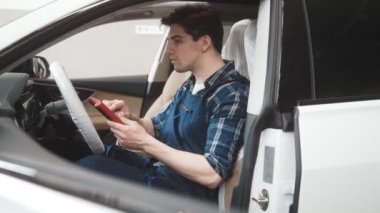 Ciddi bir oto tamircisi garajda bilgisayar kontrolü yapıyor.