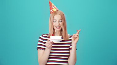 Doğum günü kadını pastaya mum üflerken stüdyodaki mavi duvarın üzerinde tek başına bir dilek tutuyor.