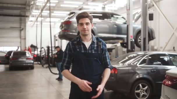 Sonriente Mecánico Hombre Mano Mientras Mira Cámara Pie Garaje Interior — Vídeo de stock