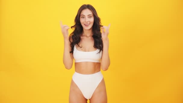 가리키는 수영복을 아름다운 스튜디오의 노란색 고립된 — 비디오