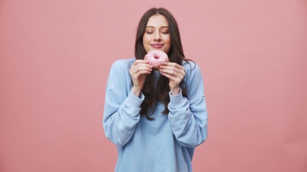 Uma Morena Positiva Comendo Donut Rosa Enquanto Assiste Filmes Isolados — Vídeo de Stock