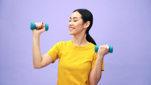 スタジオの紫色の背景に隔離された設備を使用してスポーツをする笑顔のアジア系韓国人女性 — ストック動画