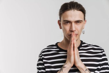 Beyaz arka planda el ele tutuşurken kameraya bakan genç beyaz adam.