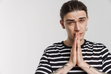 Beyaz arka planda el ele tutuşurken kameraya bakan genç beyaz adam.