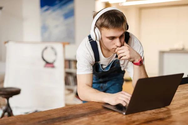 Hombre Joven Auriculares Usando Ordenador Portátil Mientras Trabaja Alfombra Artesanal — Foto de Stock
