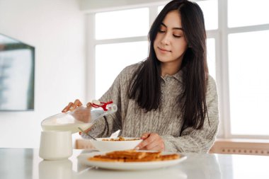 Sabahları mısır gevreği yiyen çekici, sağlıklı genç bir kadın.