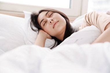 Yatakta yatan çekici, gülümseyen bir genç kadına yaklaş.