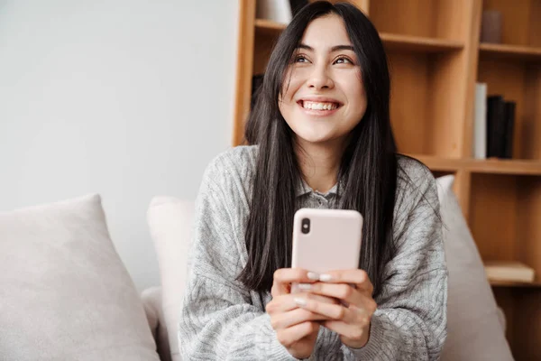 Joyful Asiatisch Frau Using Mobile Phone Während Sitzen Auf Couch — Stockfoto