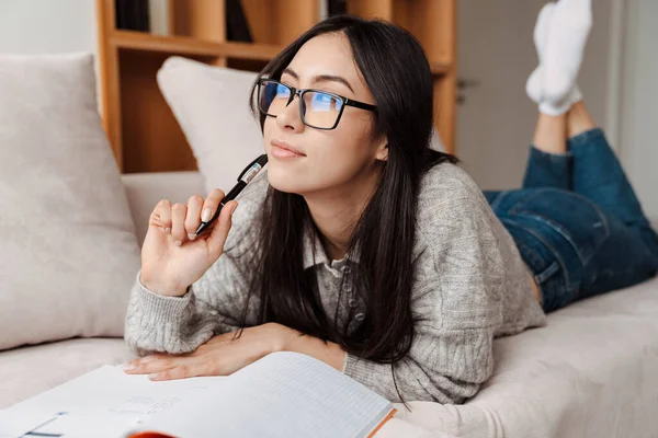 Pleased Asiatisch Student Mädchen Doing Homework Während Liegend Auf Couch — Stockfoto