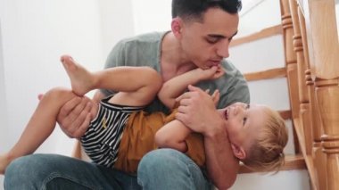 Evdeki basamaklarda oturmuş oğlunu öpen bir baba.