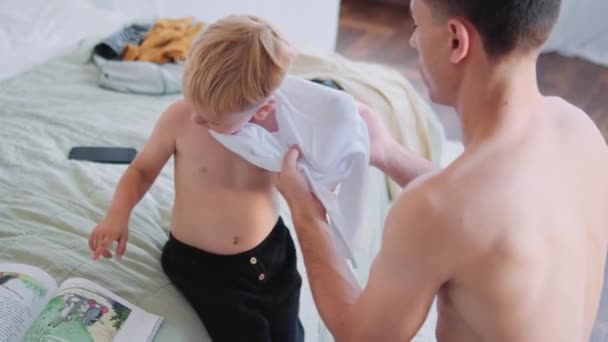 Ένας Πατέρας Βάζει Ρούχα Στο Γιο Του Στο Σπίτι — Αρχείο Βίντεο
