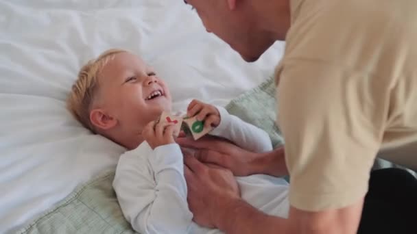 Niño Feliz Acostado Cama Mientras Padre Juega Con Casa — Vídeo de stock