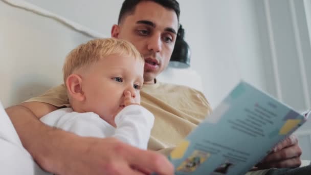 Niño Pequeño Escuchando Padre Leyendo Libro Para Casa — Vídeos de Stock