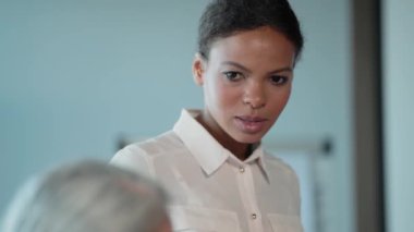 Ciddi bir Afrikalı Amerikalı iş kadını konferansta beyin fırtınası sırasında bir grup insanla çalışıyor.