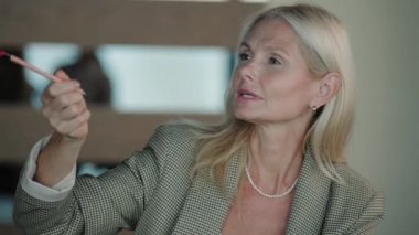 Yetişkin, sarışın bir iş kadını konferans sırasında konuşmacıyla konuşuyor.