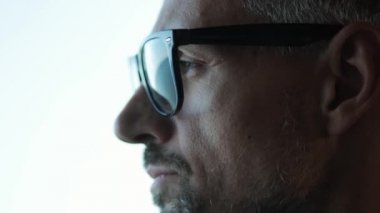 Olgun bir iş adamının ofiste duran gözlük taktığı yakın plan bir görüntü.