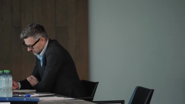 オフィスのテーブルに座っている成熟したビジネスマンの側面図 — ストック動画