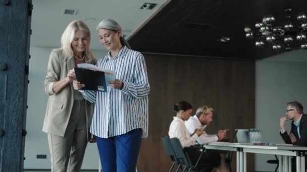 Δύο Ικανοποιημένες Γυναίκες Επιχειρηματικοί Εταίροι Συζητούν Σχέδια Εργασίας Που Κατέχουν — Αρχείο Βίντεο