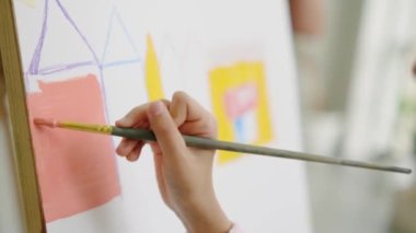 Modern sanat okulunda resim yapan küçük bir kızın yakın plan görüntüsü.