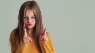 Stüdyoda gri duvarın üzerinde dans eden mutlu küçük bir kız.