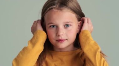 Gülümseyen küçük bir kız aynaya bakıyor. Stüdyodaki gri duvarın üzerinden izole edilmiş.