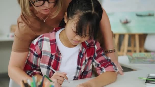 Una Hermosa Chica Asiática Dibujando Usando Lápices Mientras Maestra Ayuda — Vídeo de stock