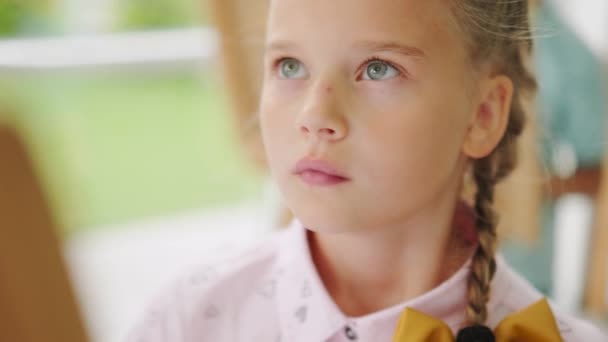학교에서 이젤을 그림을 그리는 소녀의 얼굴을 가까이 — 비디오