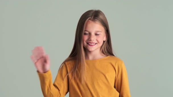 Une Petite Fille Souriante Agitant Main Debout Isolée Sur Mur — Video